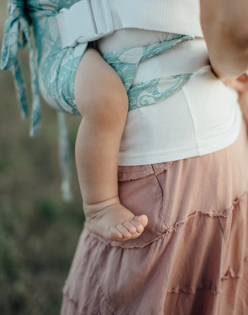 A Nebraska baby is being worn by their mom in a buckle carrier.