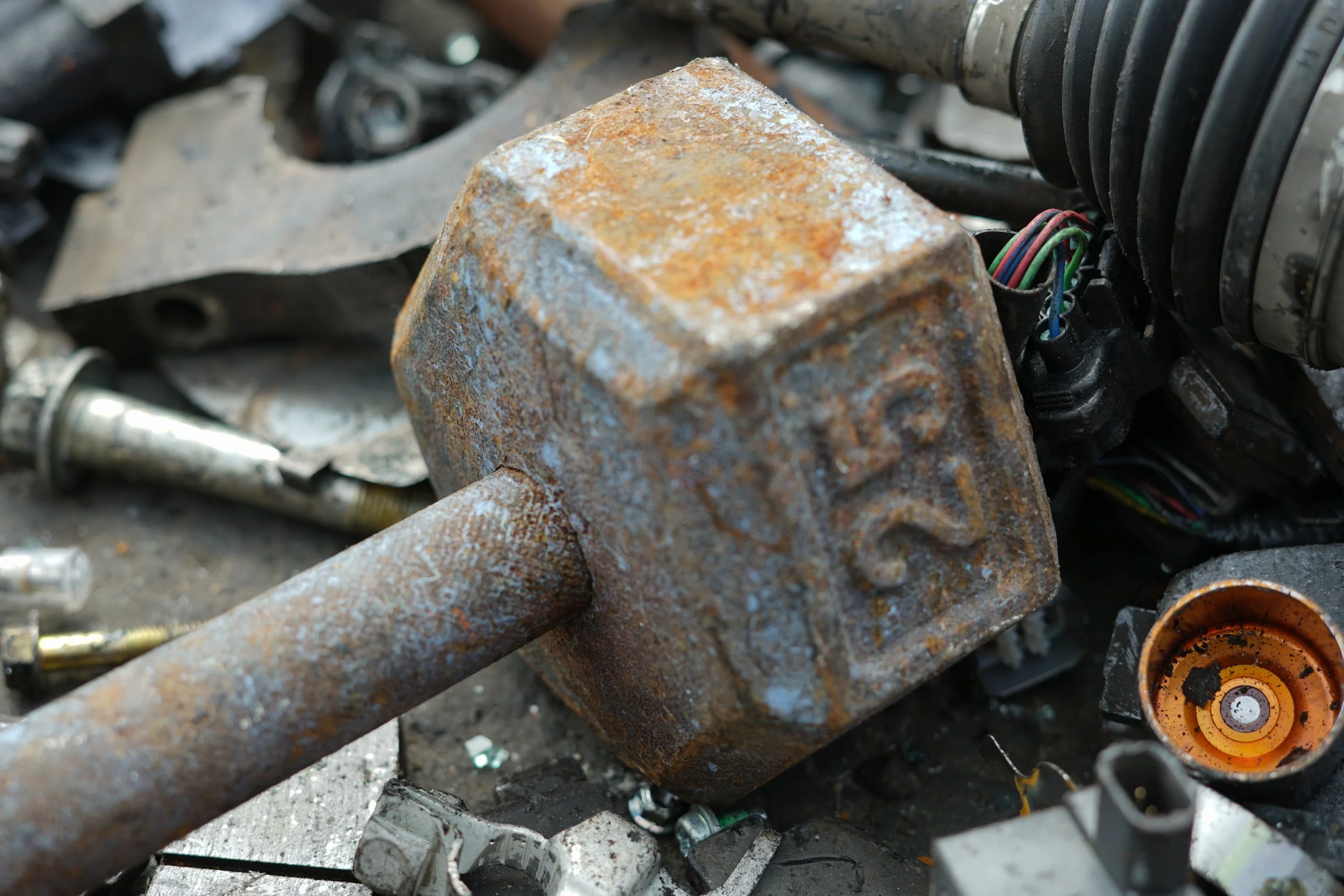 Rusty metal barbell weight on dismantled electronic and automotive recyclables.