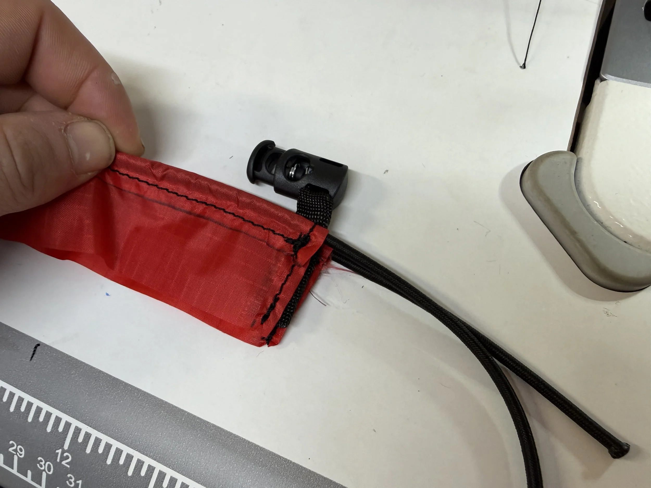 Tack the webbing to itself with a stitch, then insert in doubled over cuff material stopper facing inwards. 