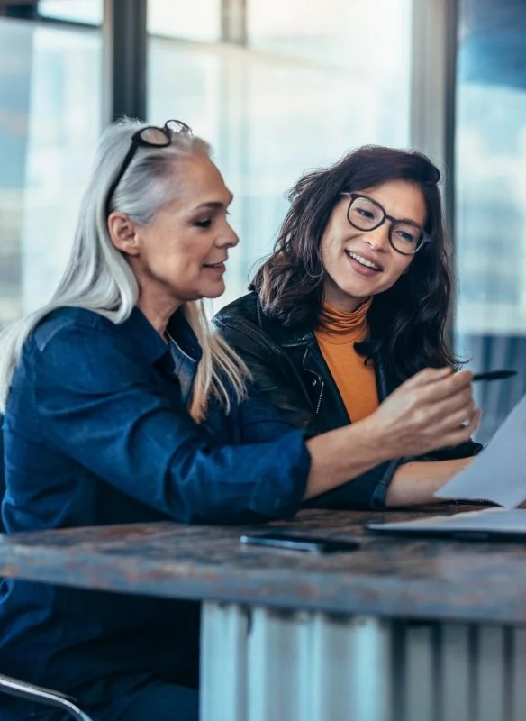 Two women, an older mentor and a younger mentee, are collaborating on strategically positioning the young woman for her job search.