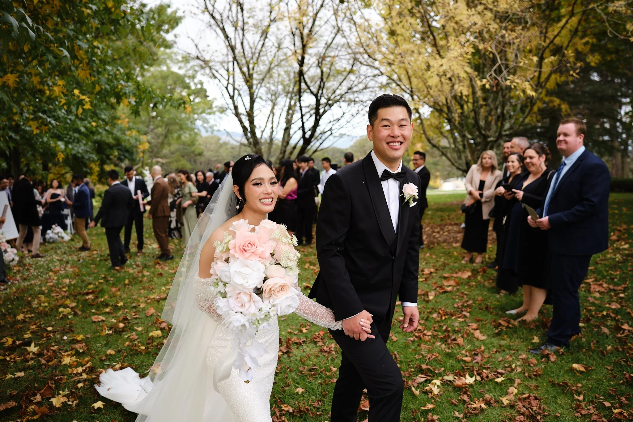 Newlyweds walking hand in hand through their guests after an outdoor wedding ceremony
