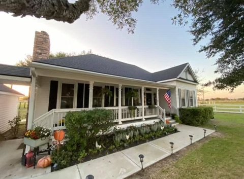 front view of a house with a porch, American flag, garden, and outdoor decor