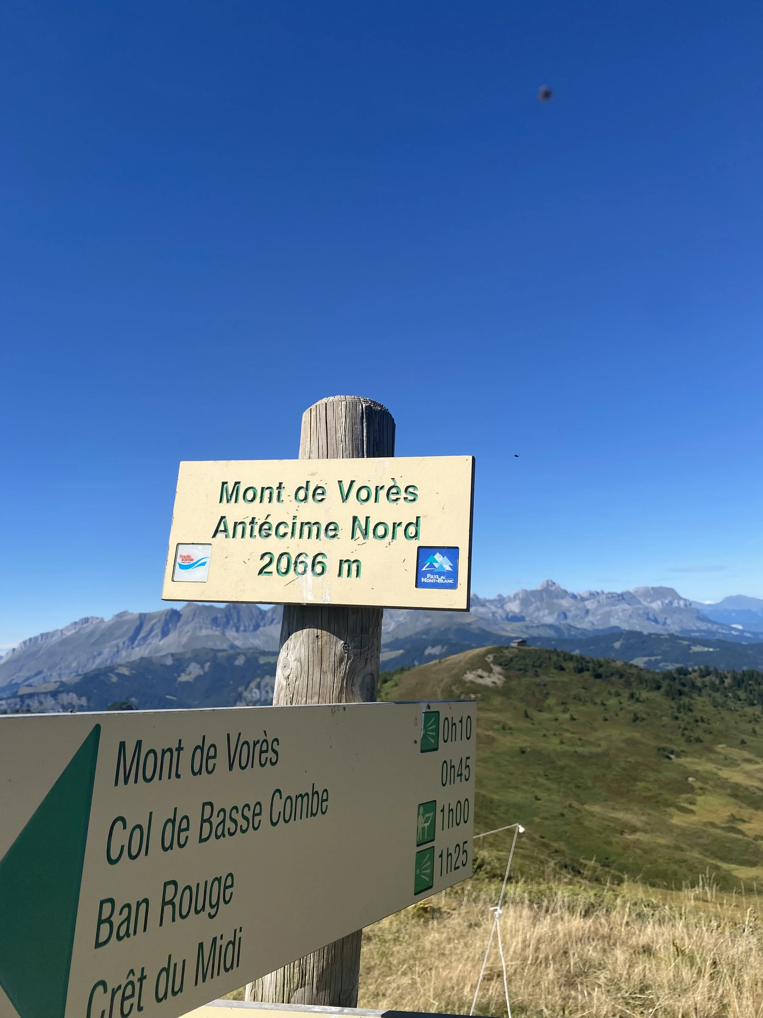 A mountain landscape with a signpost indicating Mont de Vorès at part of the Mont Blanc range, 2066 meters high, with a hiking trail on simple living mountain retreats