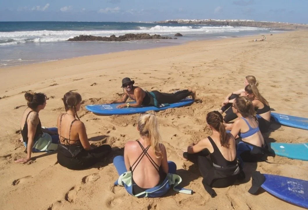 Group of girls in Fuerteventura having a group surf session with willing to surf