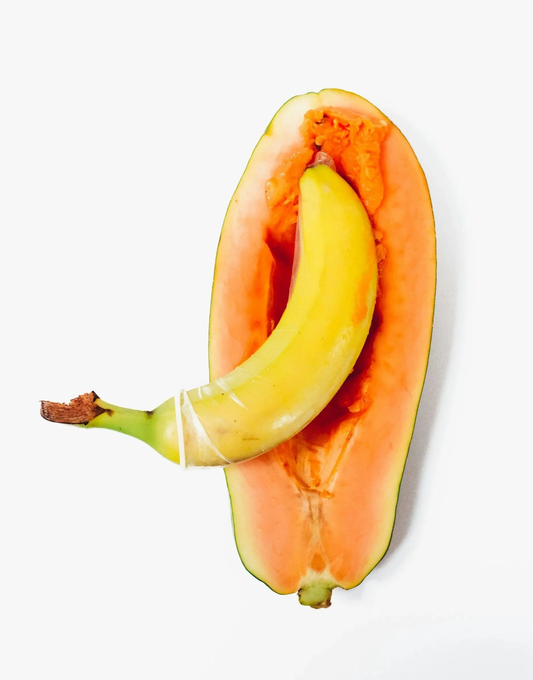 Close-up of a papaya with orange flesh and yellow banana inside, on a white background.