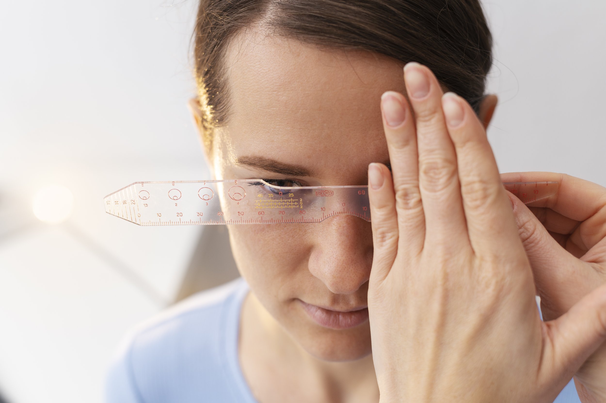 A woman measuring her forehead with a transparent ruler.