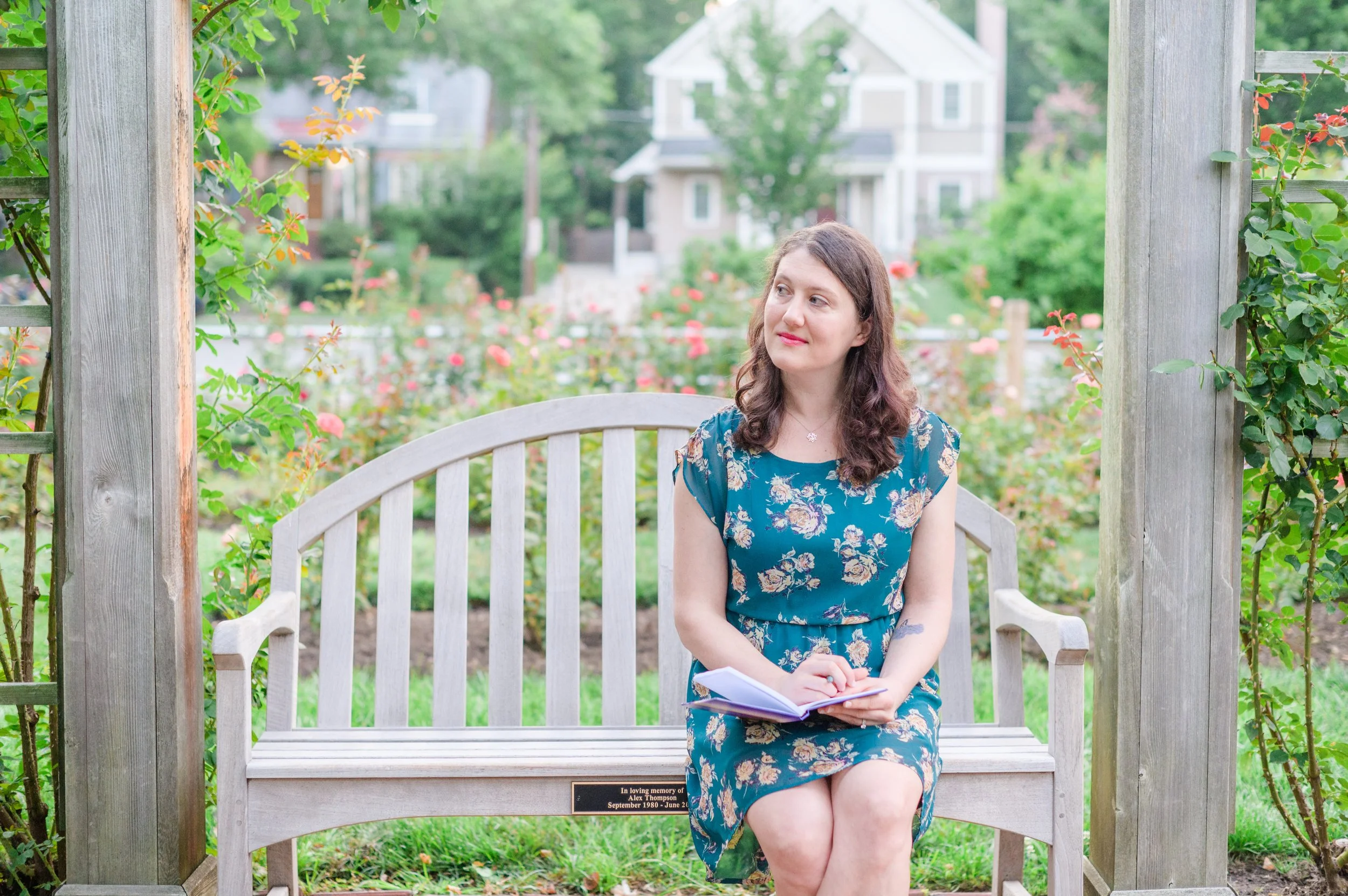 Katie LaCelle sitting on a park bench with a journal, looking thoughtful