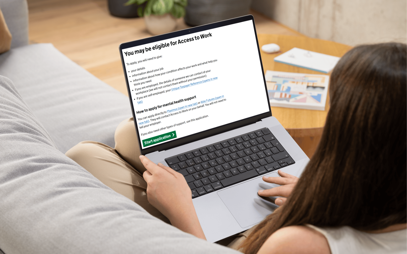 Woman sitting on sofa with a laptop open on her lap with the access to work eligibility page open