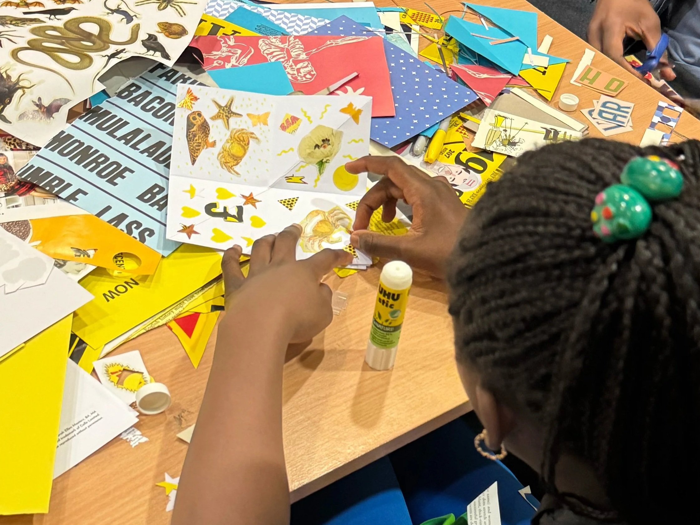 Hands sorting through collage paper and images during a youth collage workshop in London