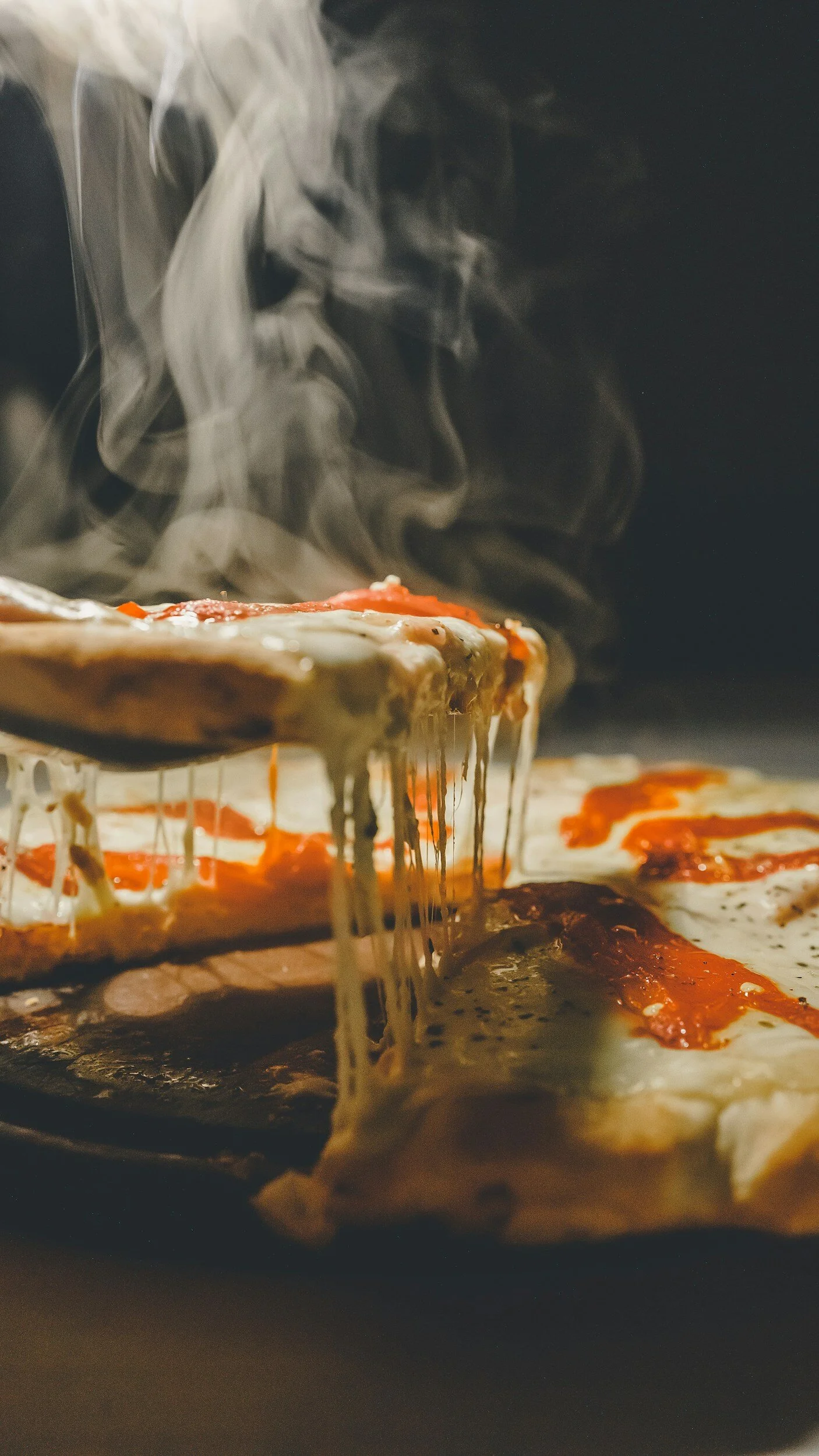 Close-up of a freshly baked pizza with melted cheese, tomato sauce, and steam rising from it.