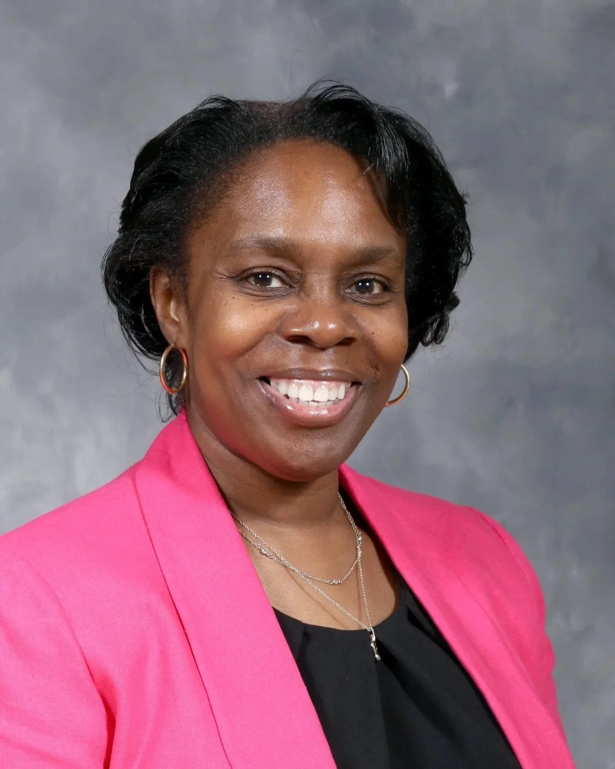 picture of a woman with short black hair and a bright pink jacket