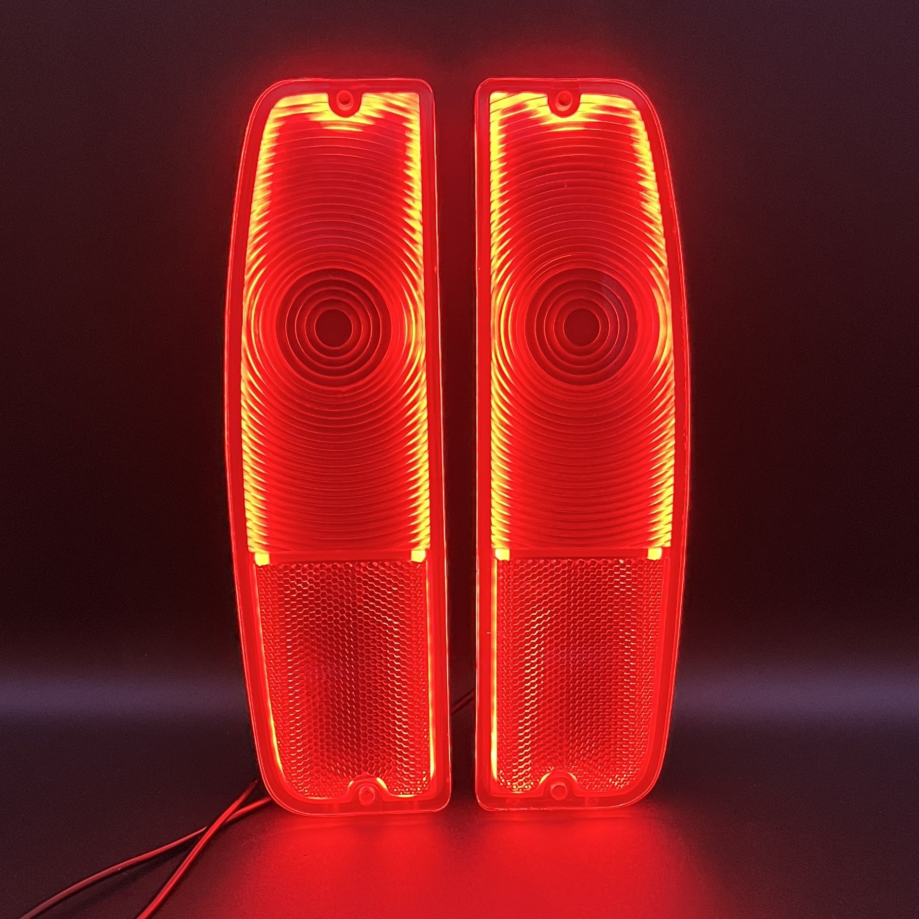 Two vertical red LED lights with concentric circle patterns, illuminated against a dark background.