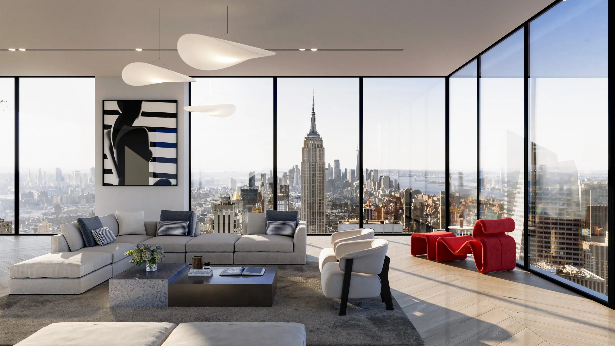 Modern living room with large floor-to-ceiling windows showing New York City skyline including the Empire State Building. The room features a white sectional sofa with blue and white pillows, a gray marble coffee table with books and flowers, white a