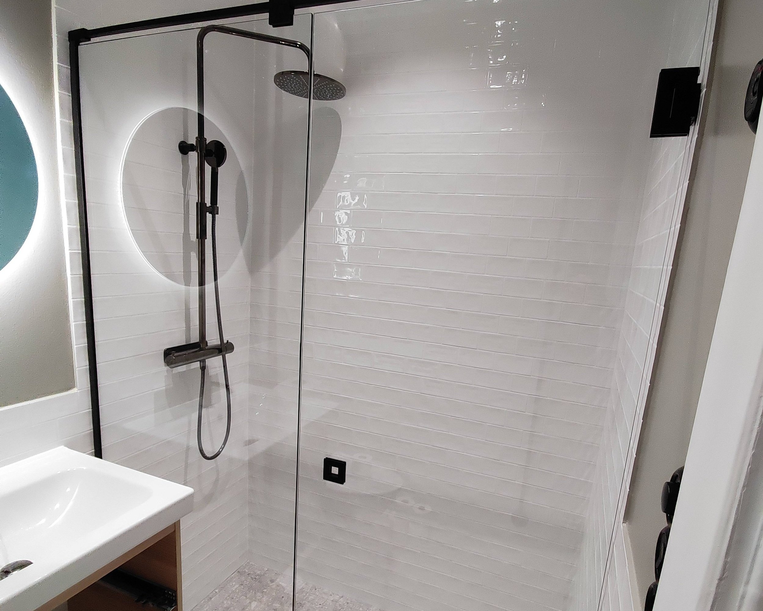 Bild på nyrenoverat duschrum efter renovering med vitt kakel och svarta detaljer