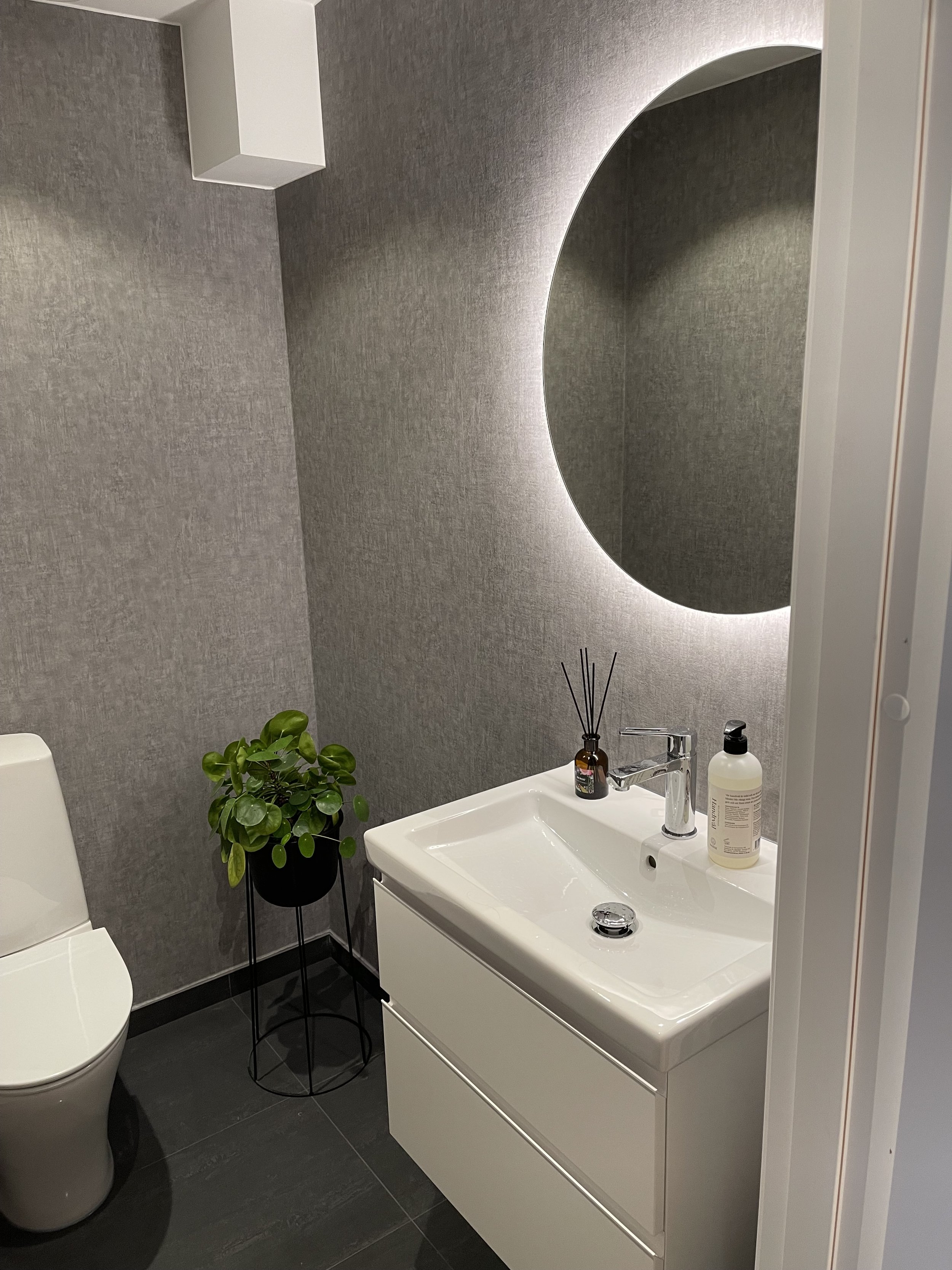 Bild på gäst wc efter renovering med gråa tapetserade väggar