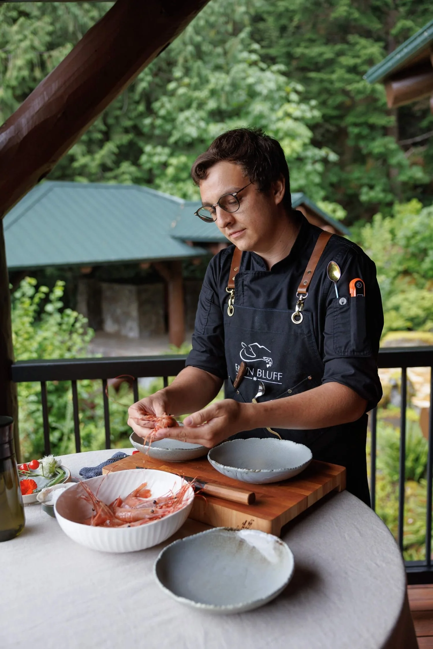 A private chef meticulously preparing fresh, local prawns on an outdoor deck at Fawn Bluff Lodge, highlighting the personalized luxury hospitality experience.