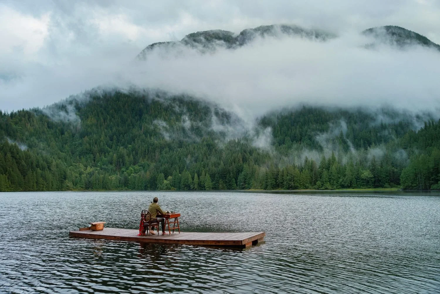 A solitary wooden desk set up on a floating dock on a misty private lake at Fawn Bluff Lodge, representing a distraction-free environment for strategic corporate planning.
