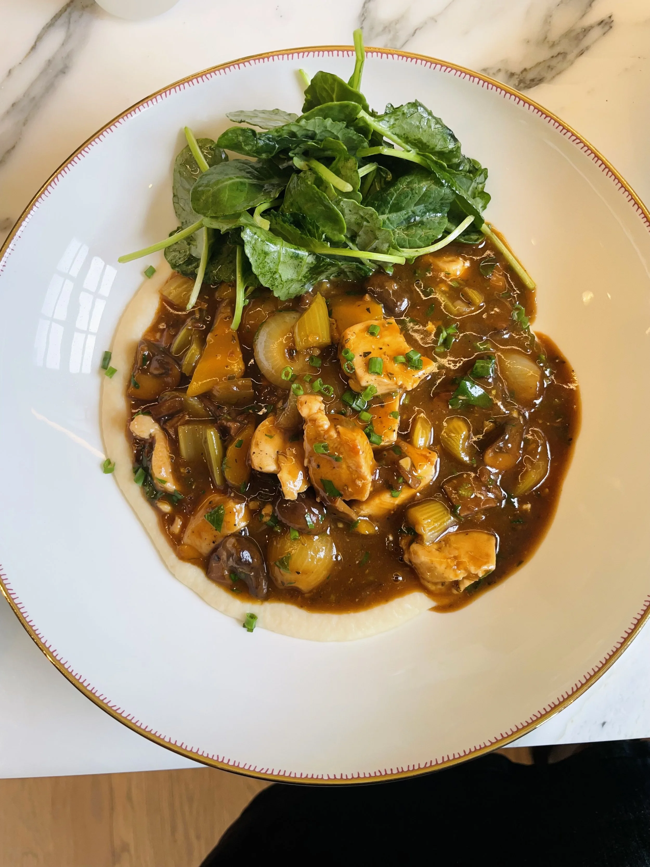 Plate of chicken and vegetable Irish stew, on top of a cauliflower mash, with a side of lemony kale on a white decorative plate.