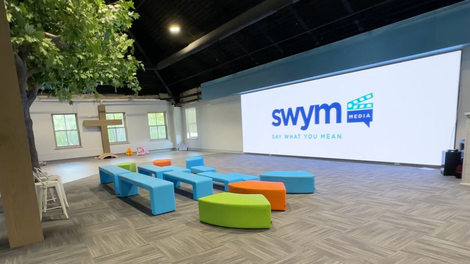 Modern church space with a large LED screen showing the SWYM Media logo