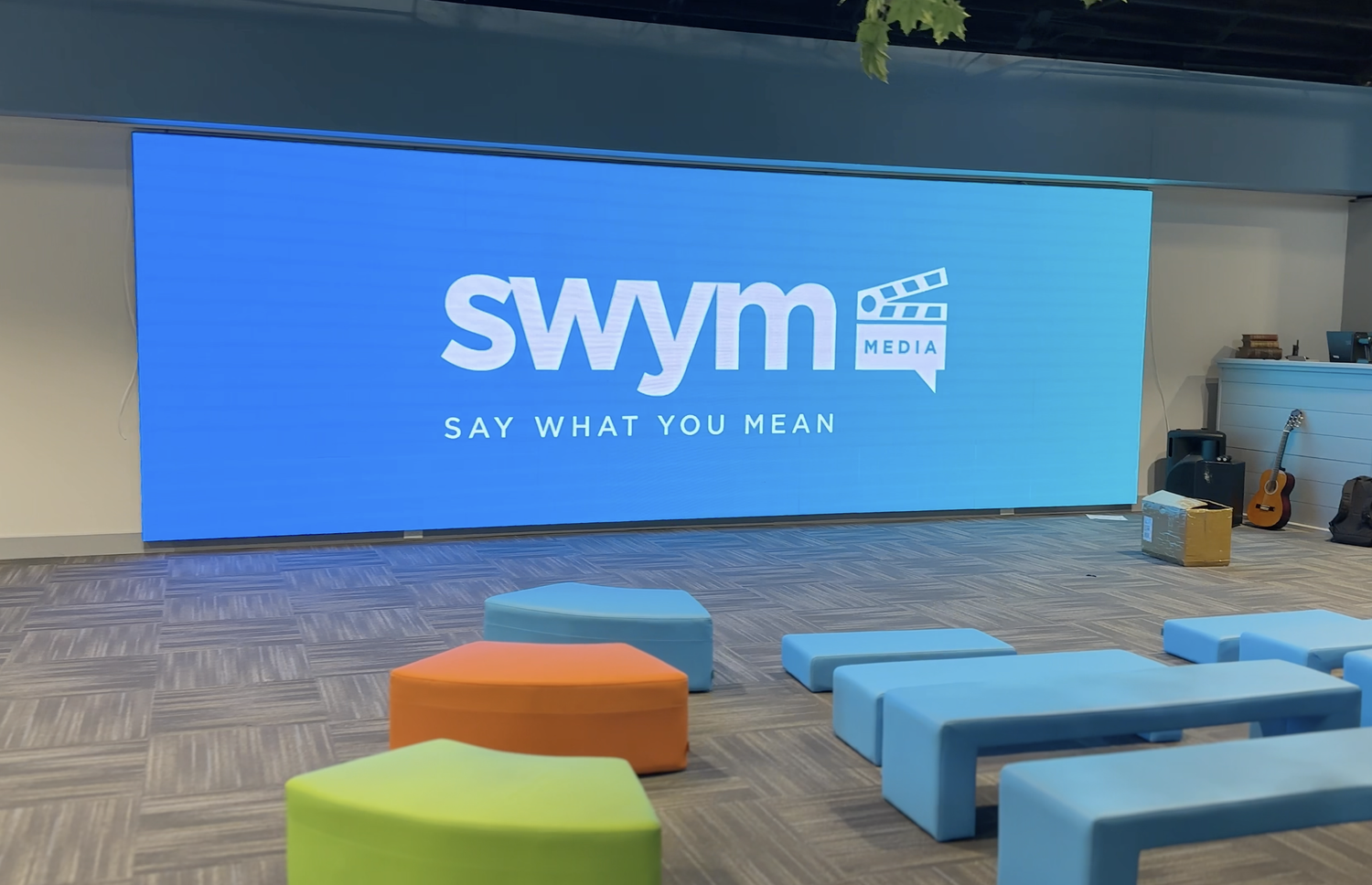 Large LED screen showing the SWYM Media logo above bench seating