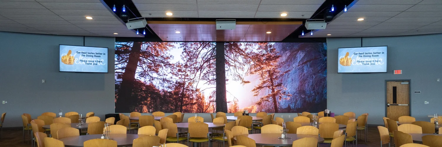 Large dining hall with an LED wall showing a forest scene