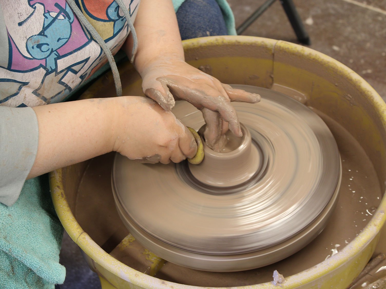 A pair of hads shaping clay on a pottery wheel.
