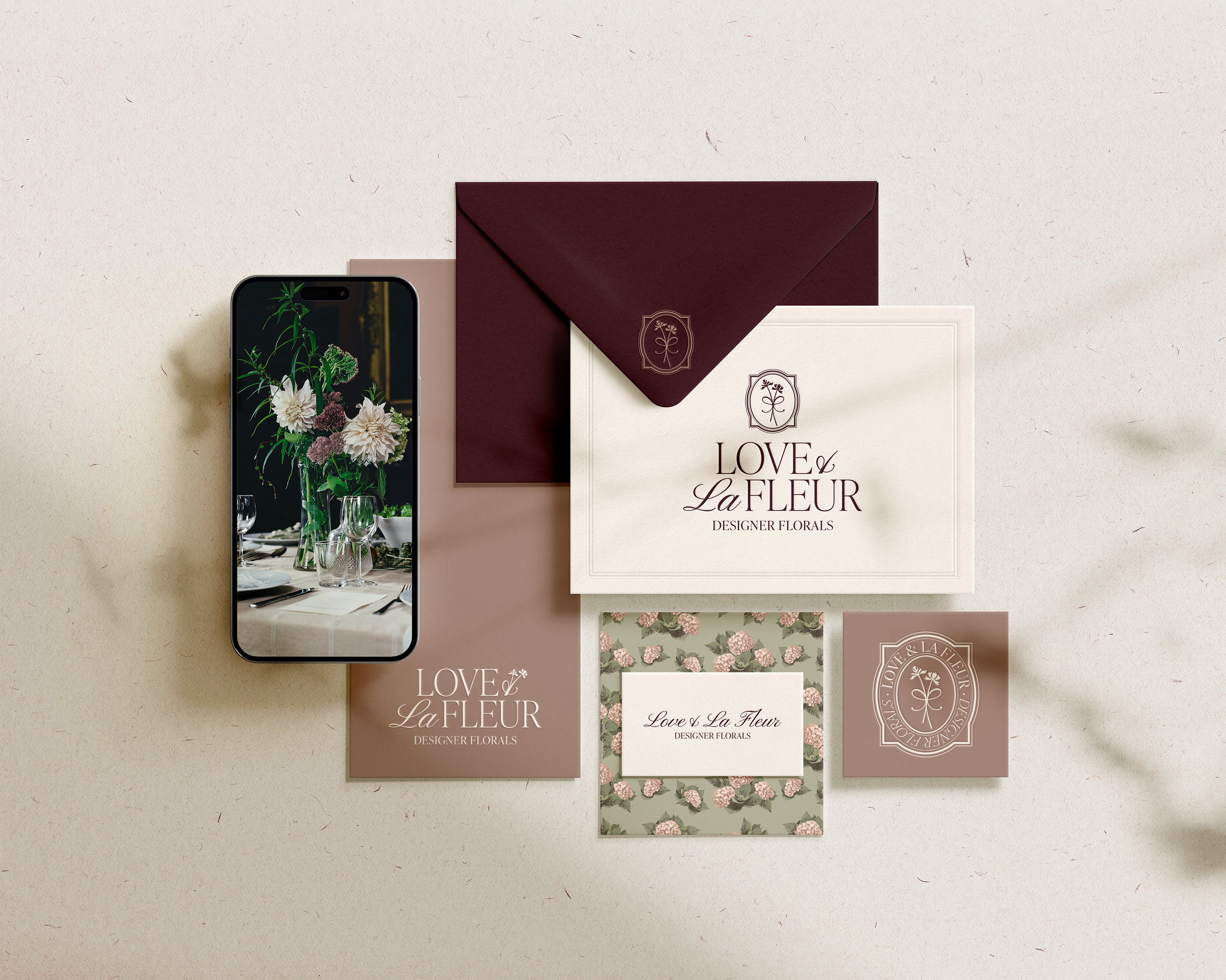 Branding materials including a phone displaying floral arrangements, an envelope, a postcard labeled 'Love La Fleur Designer Florals', and floral patterned cards.