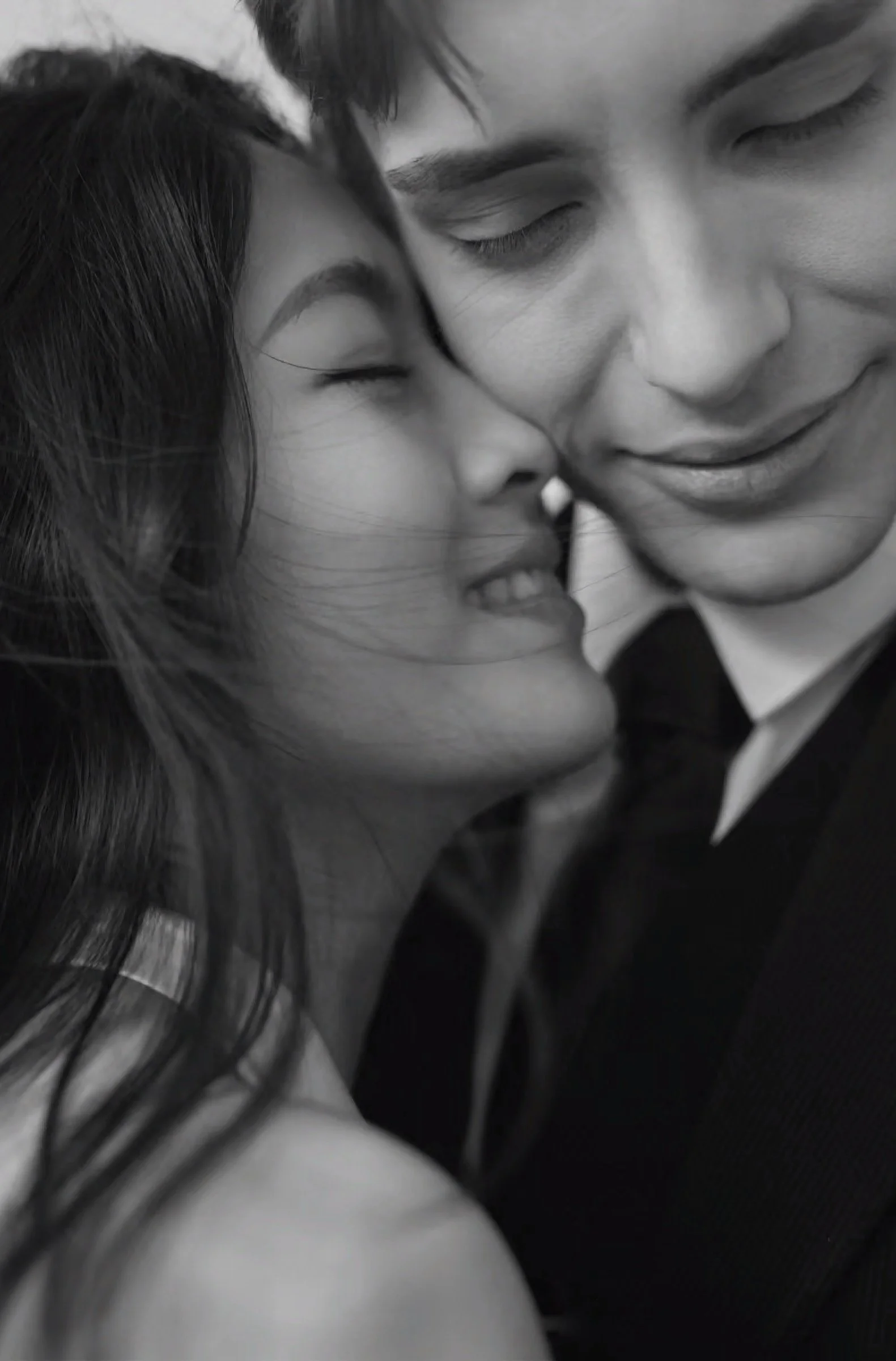 Black and white close-up photo of a couple smiling with their faces close together, showing affection and intimacy.