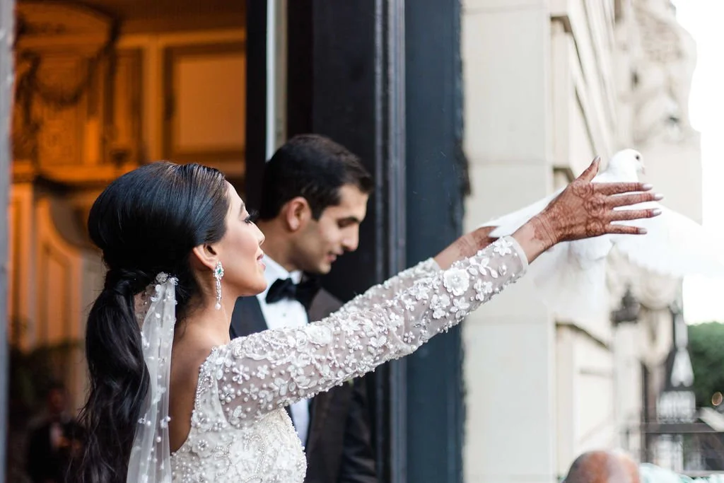 Bride releasing a white dove at her wedding, with groom standing behind her.