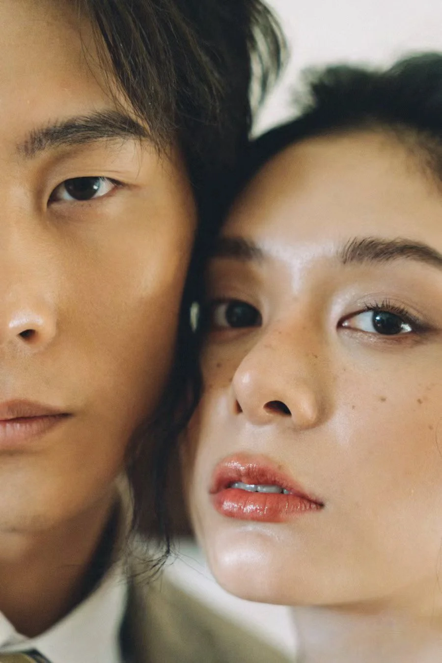 Close-up of a young man and woman with their faces closely together, both looking at the camera.