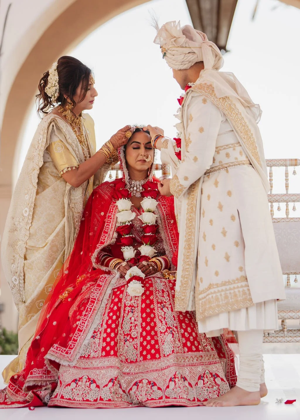Indian wedding ceremony with bride and groom in traditional attire, performing a ritual in Hilton Santa Barbara beachfront.