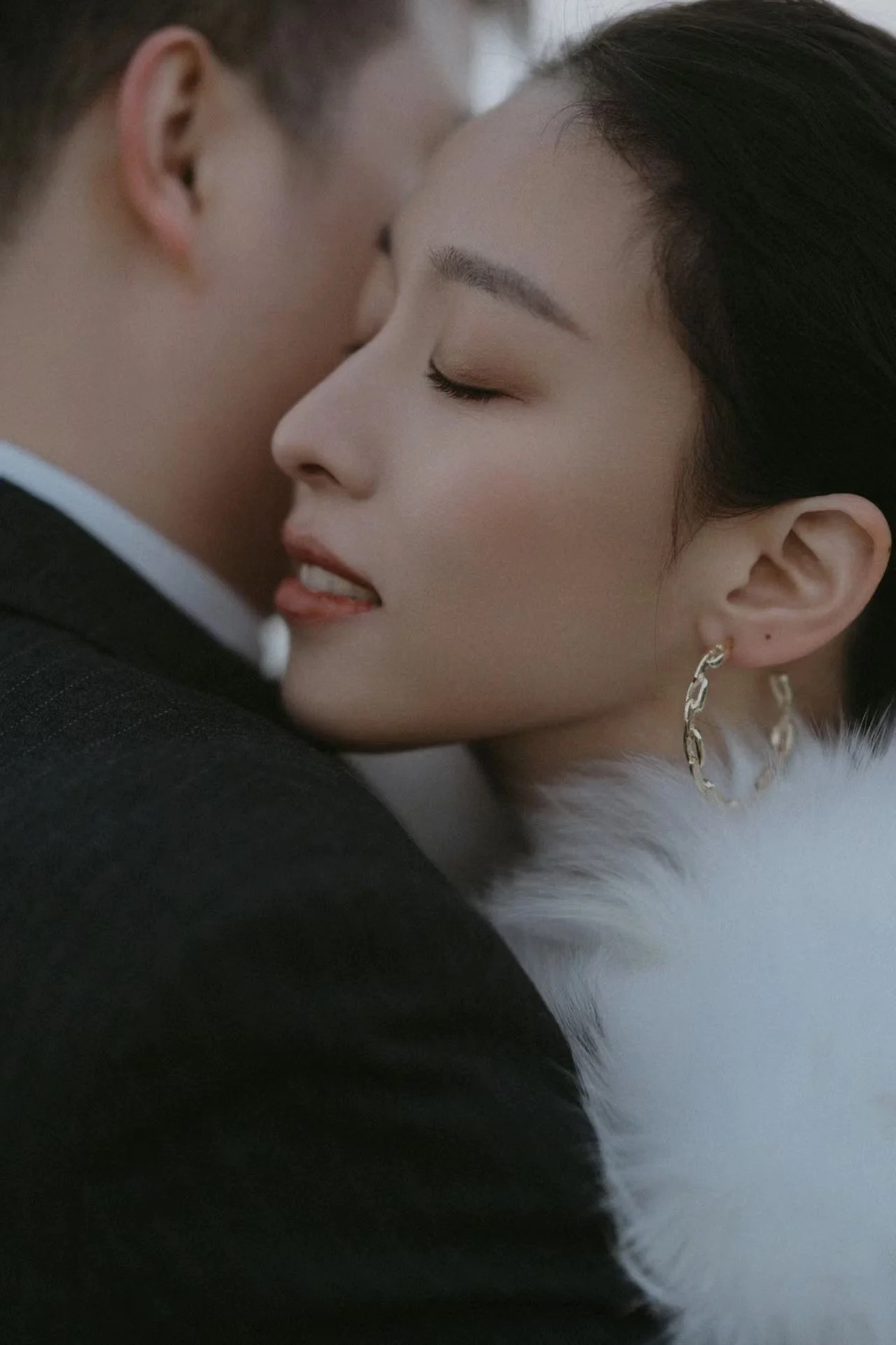 A man and woman in an intimate close-up moment, eyes closed, with their foreheads touching and the woman's lips slightly parted.