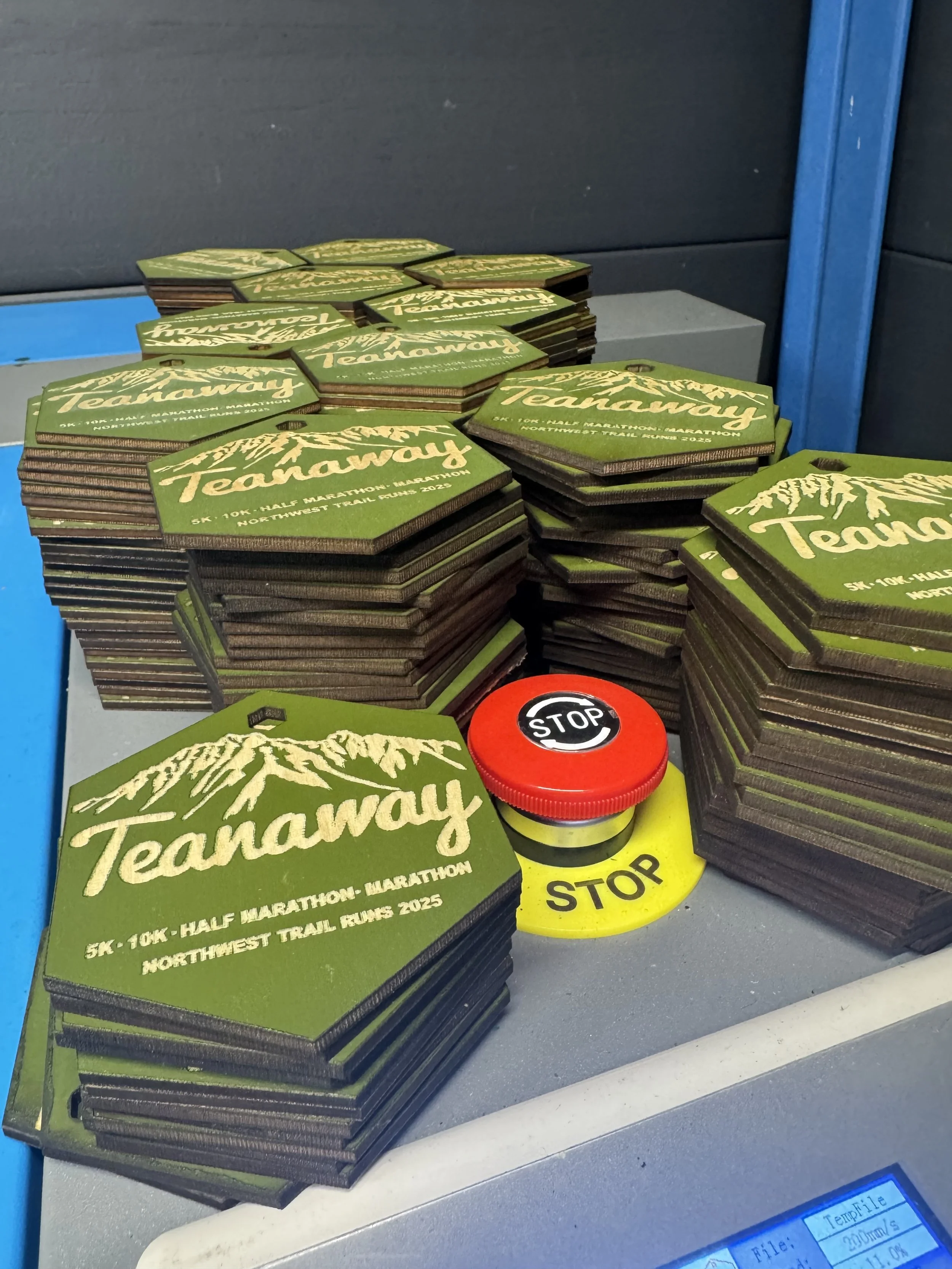 Stacks of green and black patches for the Teanaway Trail Run 2023, alongside stop signs and a yellow caution tape on a table.