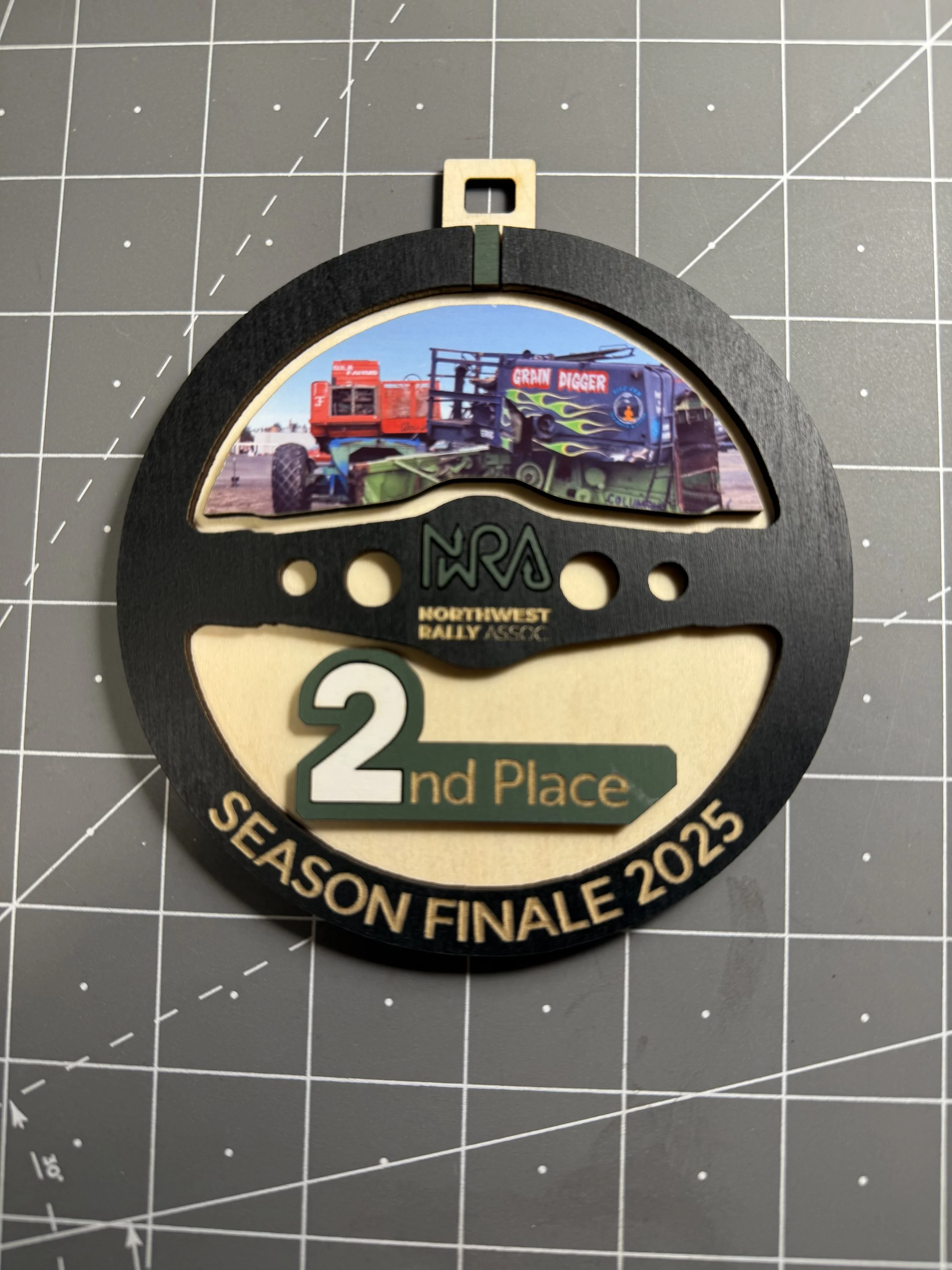 A circular award medal with the logo and text of the Northwest Rally Association, featuring a picture of a rally car, and indicating second place in the season finale of 2025.