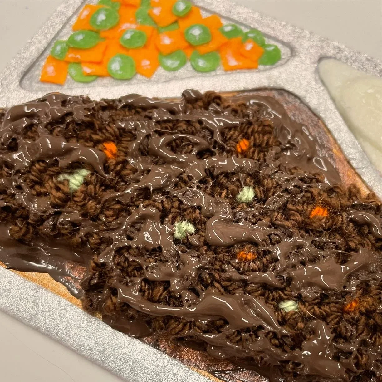 I am both extremely disgusted and disturbed about my new Thesis piece... yep. That's meatloaf. Made out of yarn (meat) and fabric paint (gravy). I hate it SO much, but love how it came out. PS... it's squishy 🥴 I never  thought this is what I'd be c