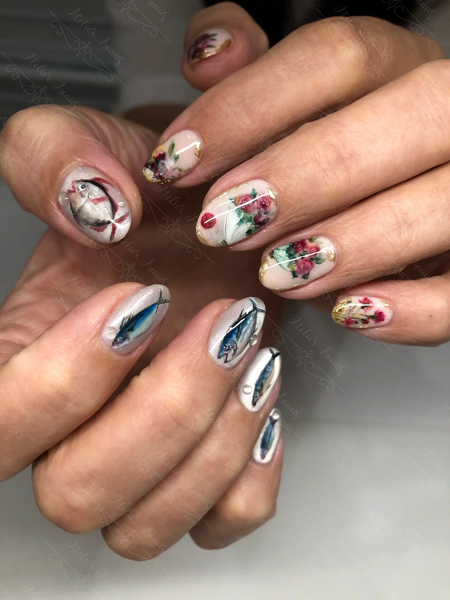 Hands with medium nails featuring hand drawn fish and rose nail art on a glossy light pink base for spring and summer.