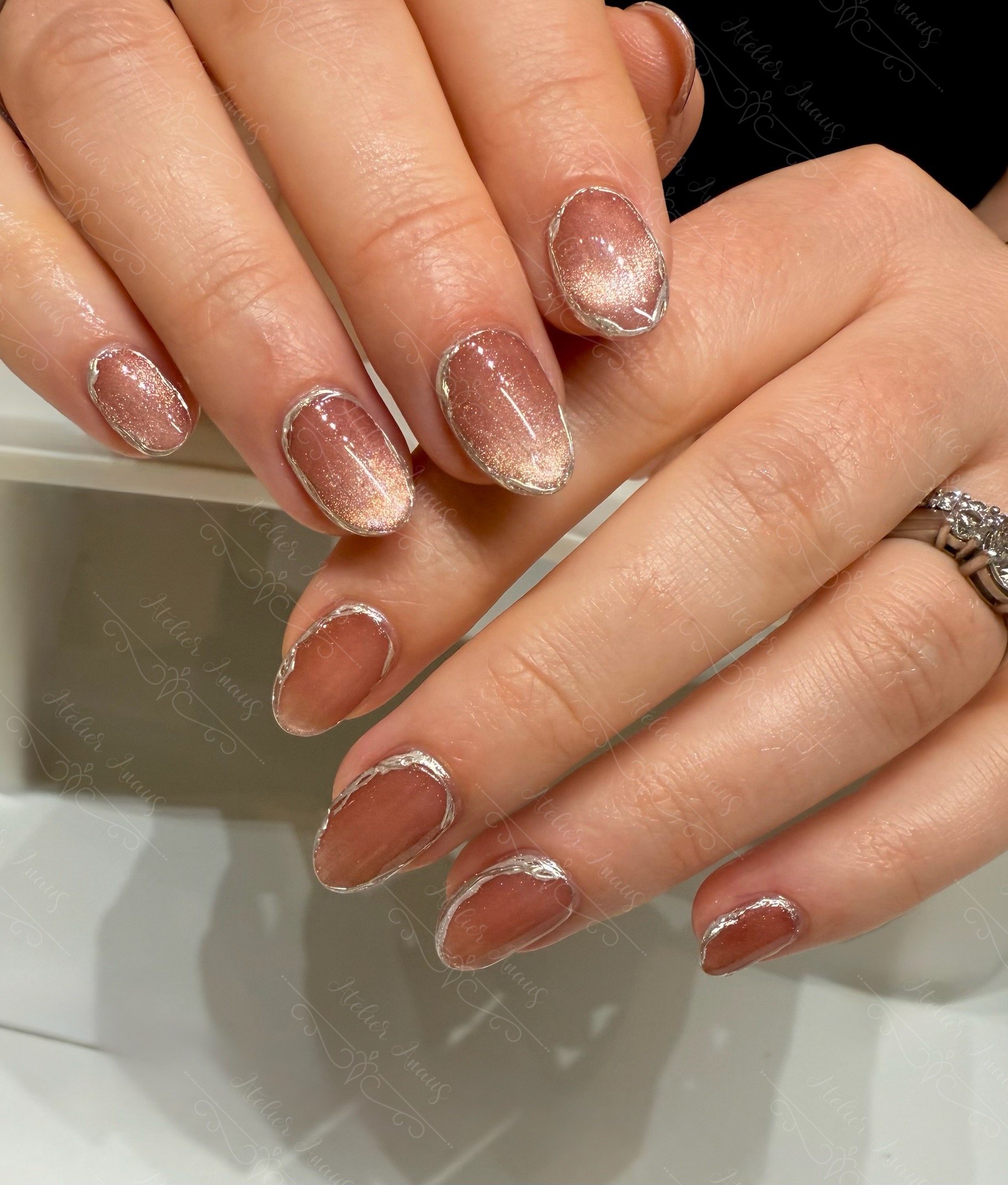 Silver circular nail art on amber cat-eye base at a nail salon in Old City.