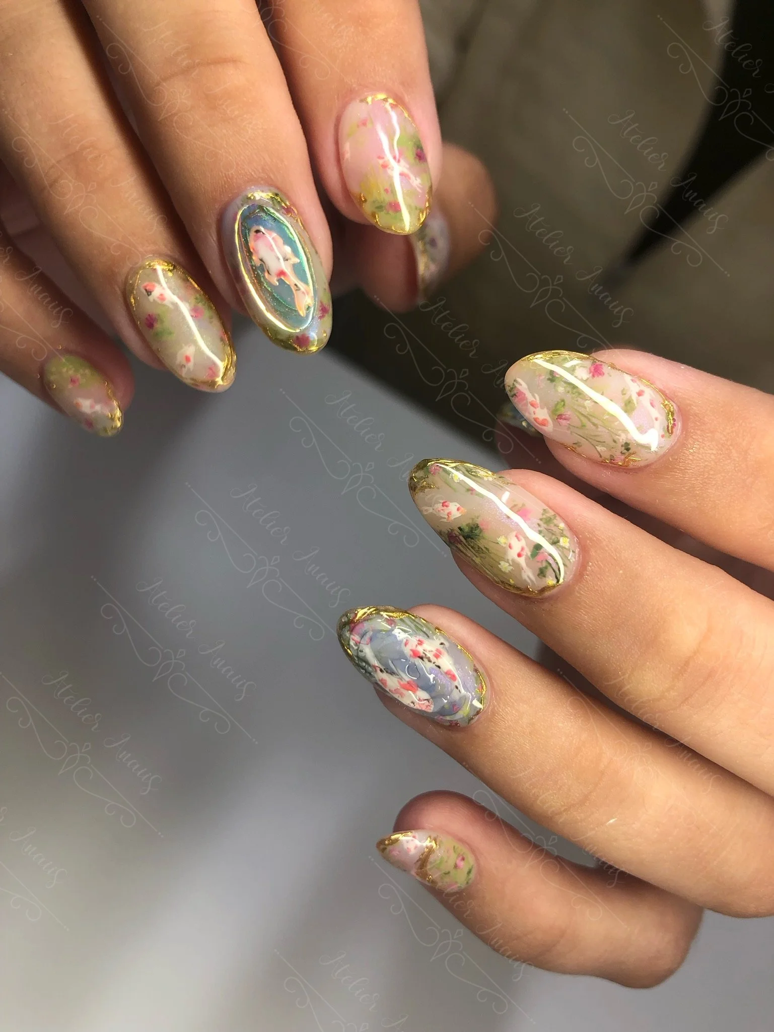 Hands with long nails featuring hand drawn impressionist nail art inspired by Monet koi pond in green, red, and blue. 