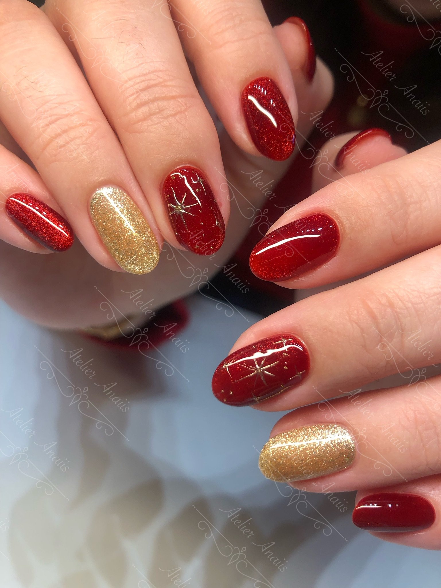 Medium nails featuring hand drawn stars on a glittering red and gold cat-eye velvet base.
