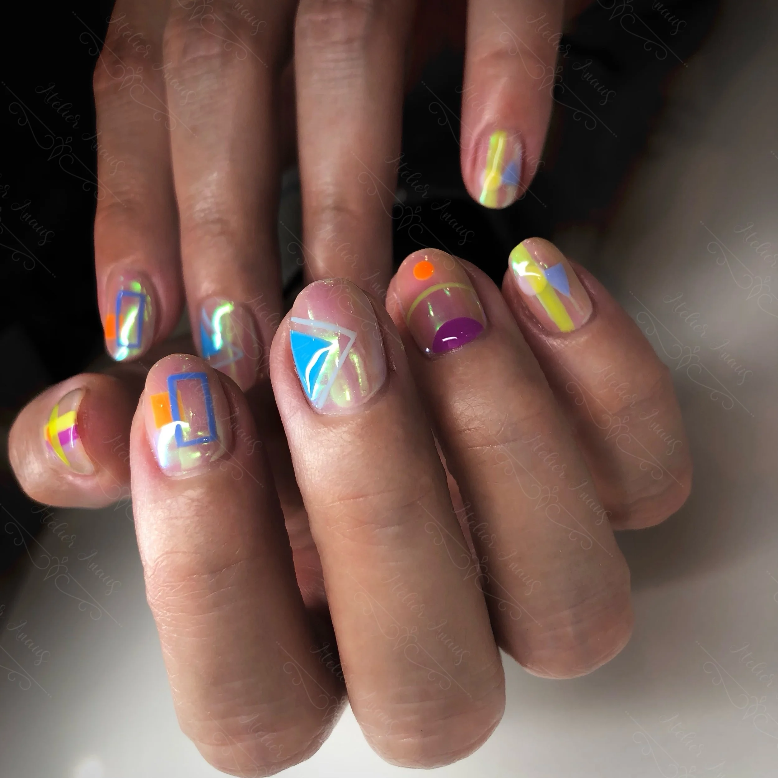 Short vacation nails featuring geometric abstract nail art in orange, blue, and yellow from a nail salon in Old City. 