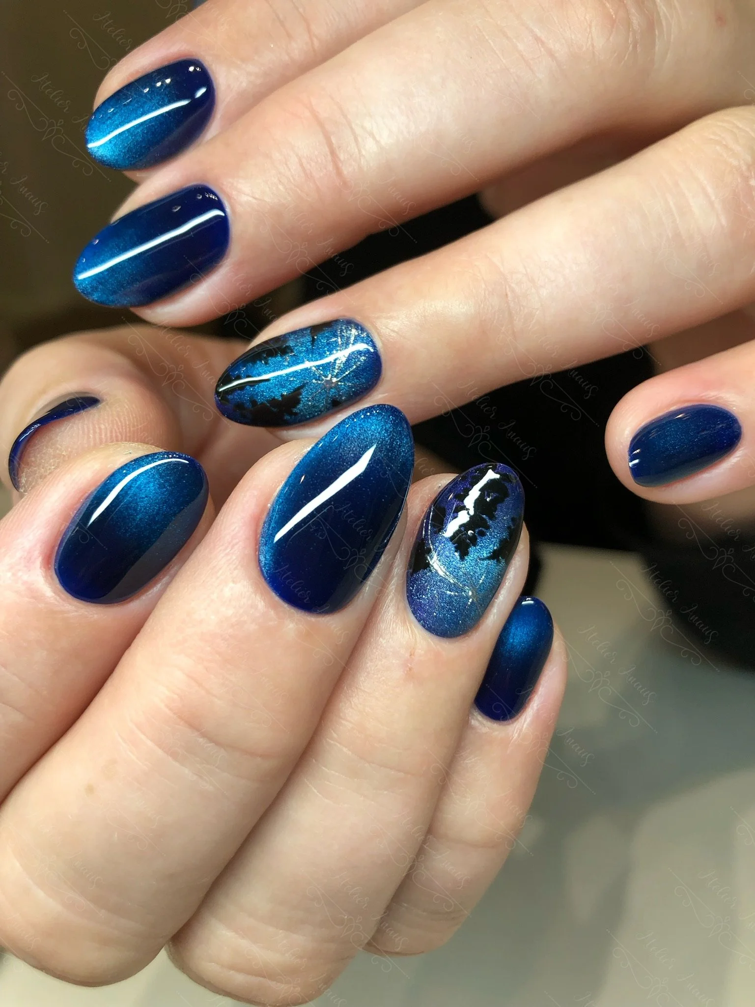 Medium length nails with dark blue cat-eye velvet gel polish with trees resembling the night sky.