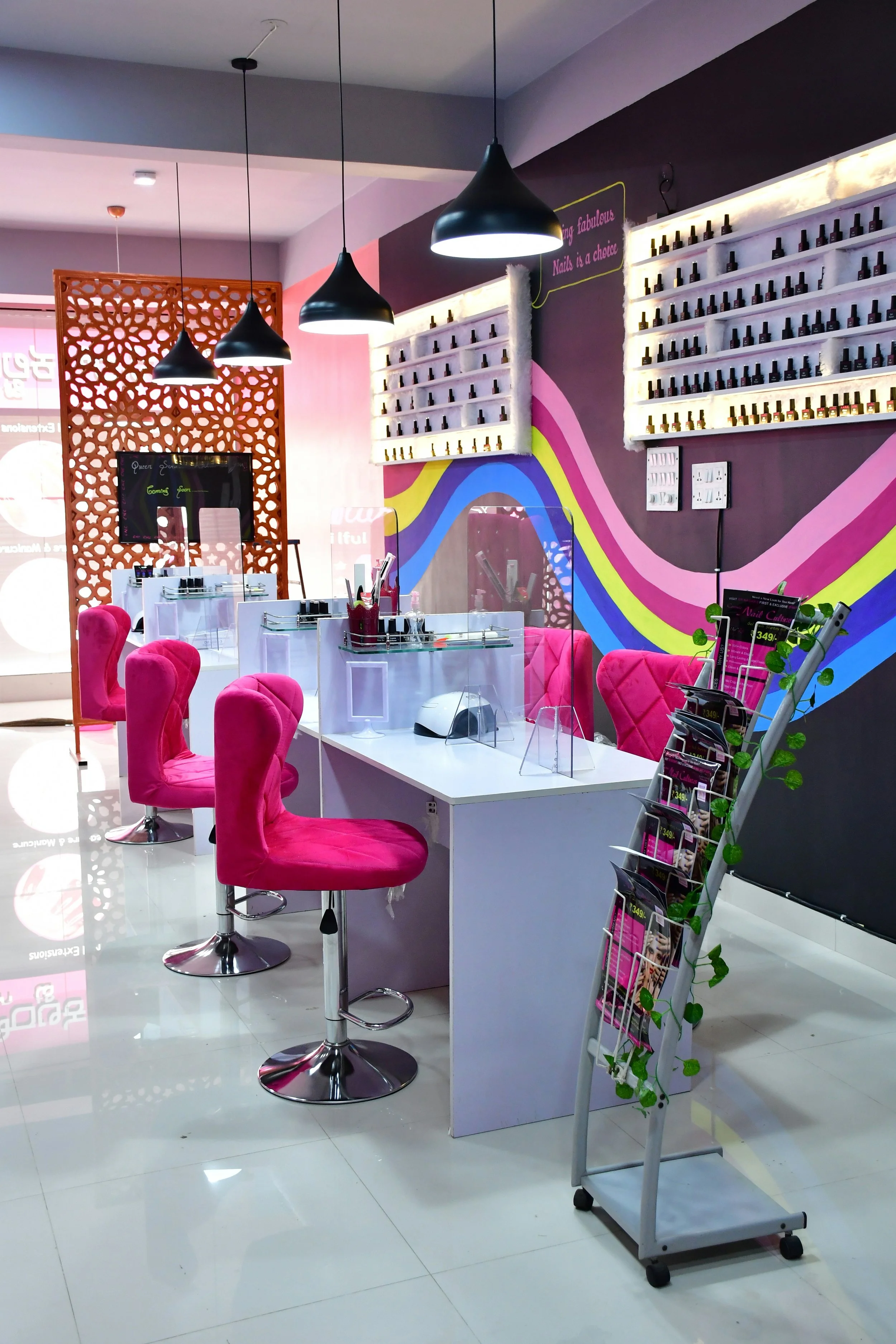 Highlighter pink chairs and rows of nail polish in a typical modern nail salon.