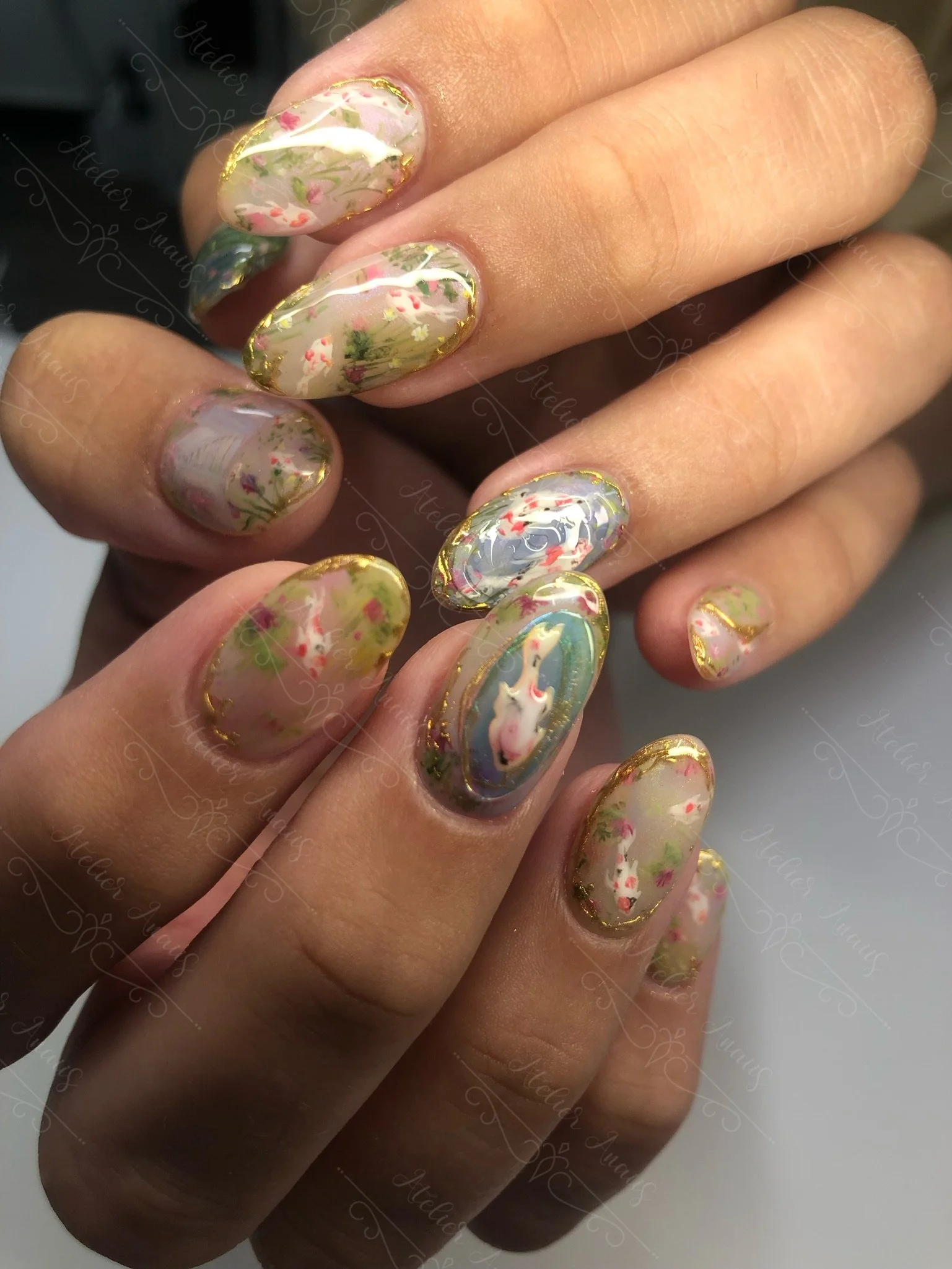 Hands with long nails featuring hand drawn impressionist nail art inspired by Monet koi pond in green, red, and blue. 