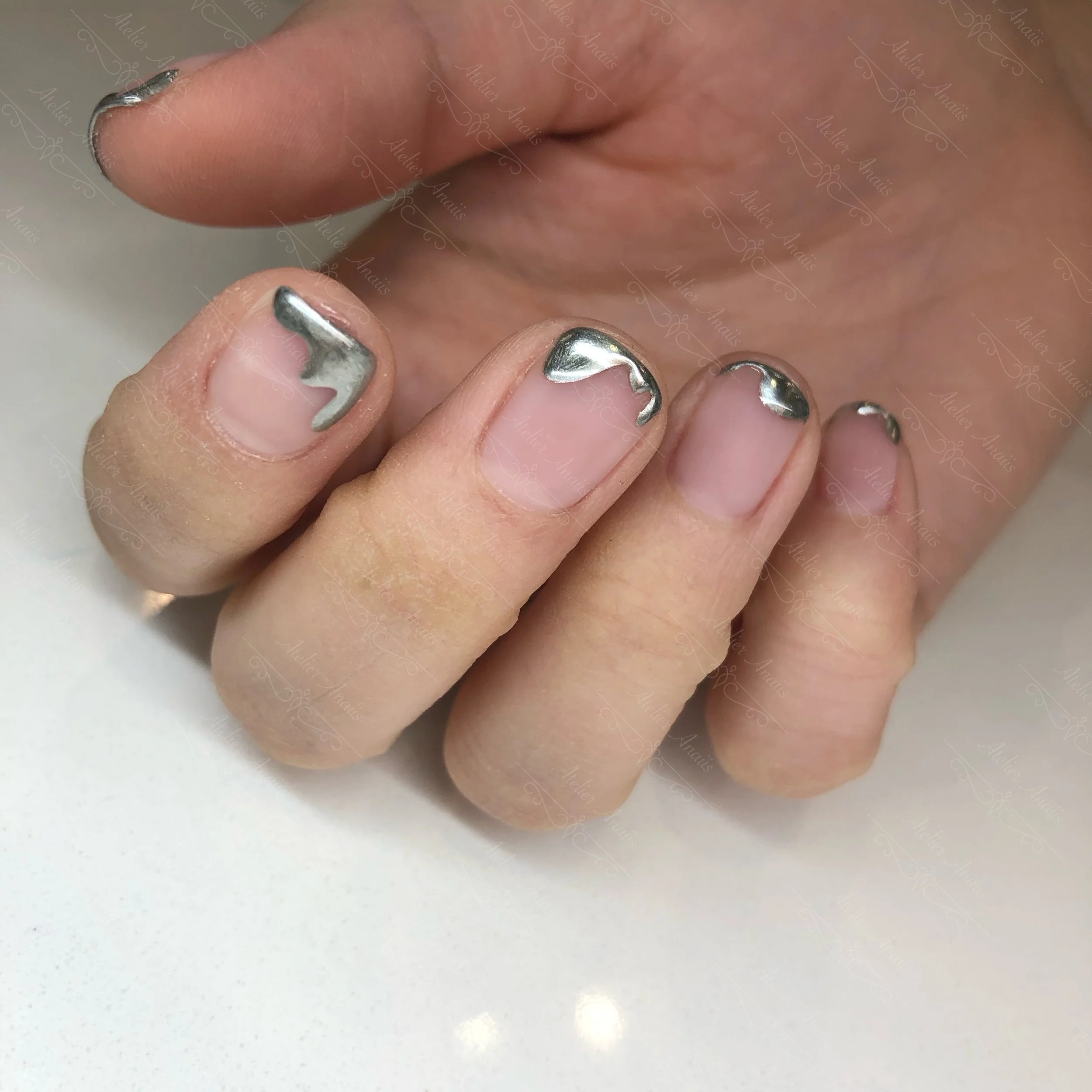 Hands with short natural nails featuring modern nail art with modern contemporary French tips that drip over a natural nail base.