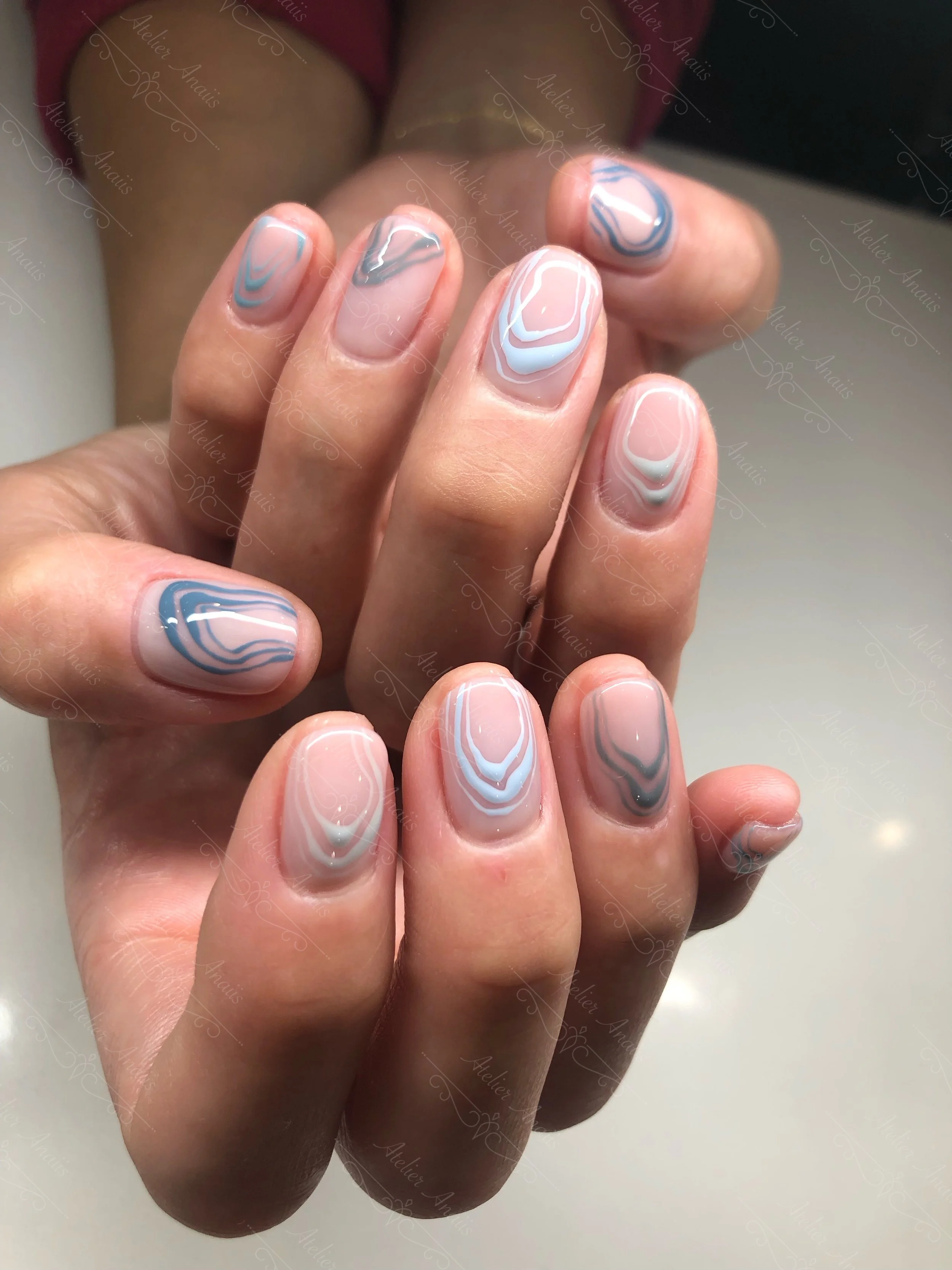Abstract nails featuring blue lines on a glossy pink base at a nail salon in Old City. 