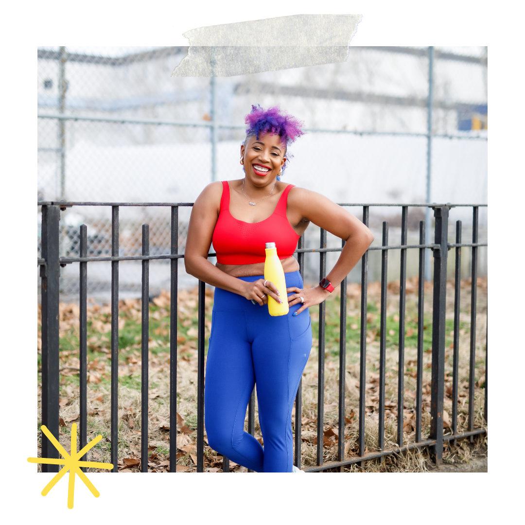 A woman, Dr. Mel Robinson-Brown, with purple hair wearing a red tank top and blue pants, smiling and holding a yellow bottle, standing outdoors by a black metal fence.