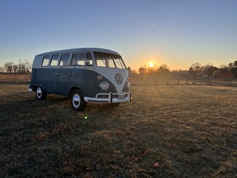 Vintage Volkswagen bus parked in a field at sunset.