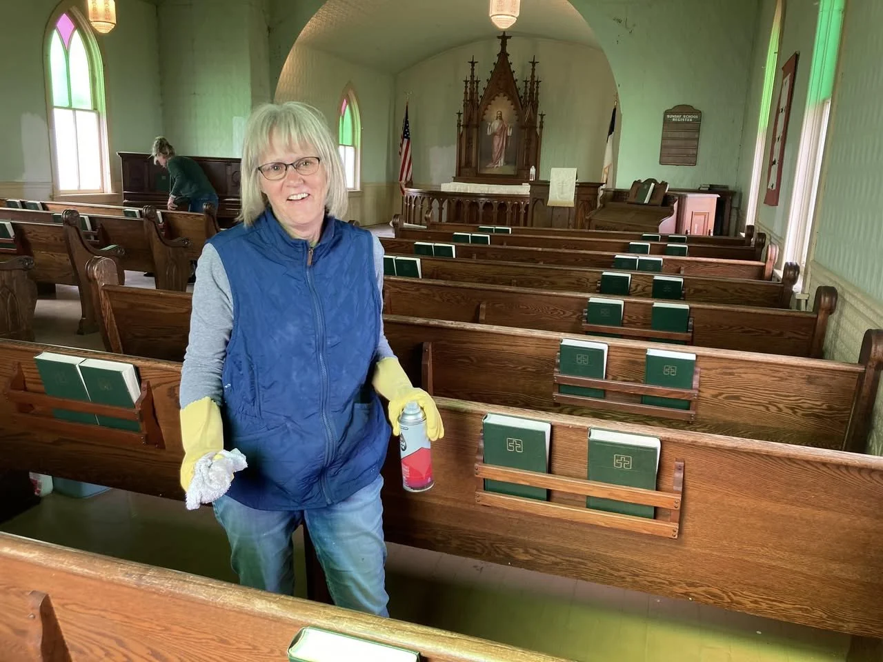 A volunteer dusts pews inside Tunbridge Lutheran Church.
