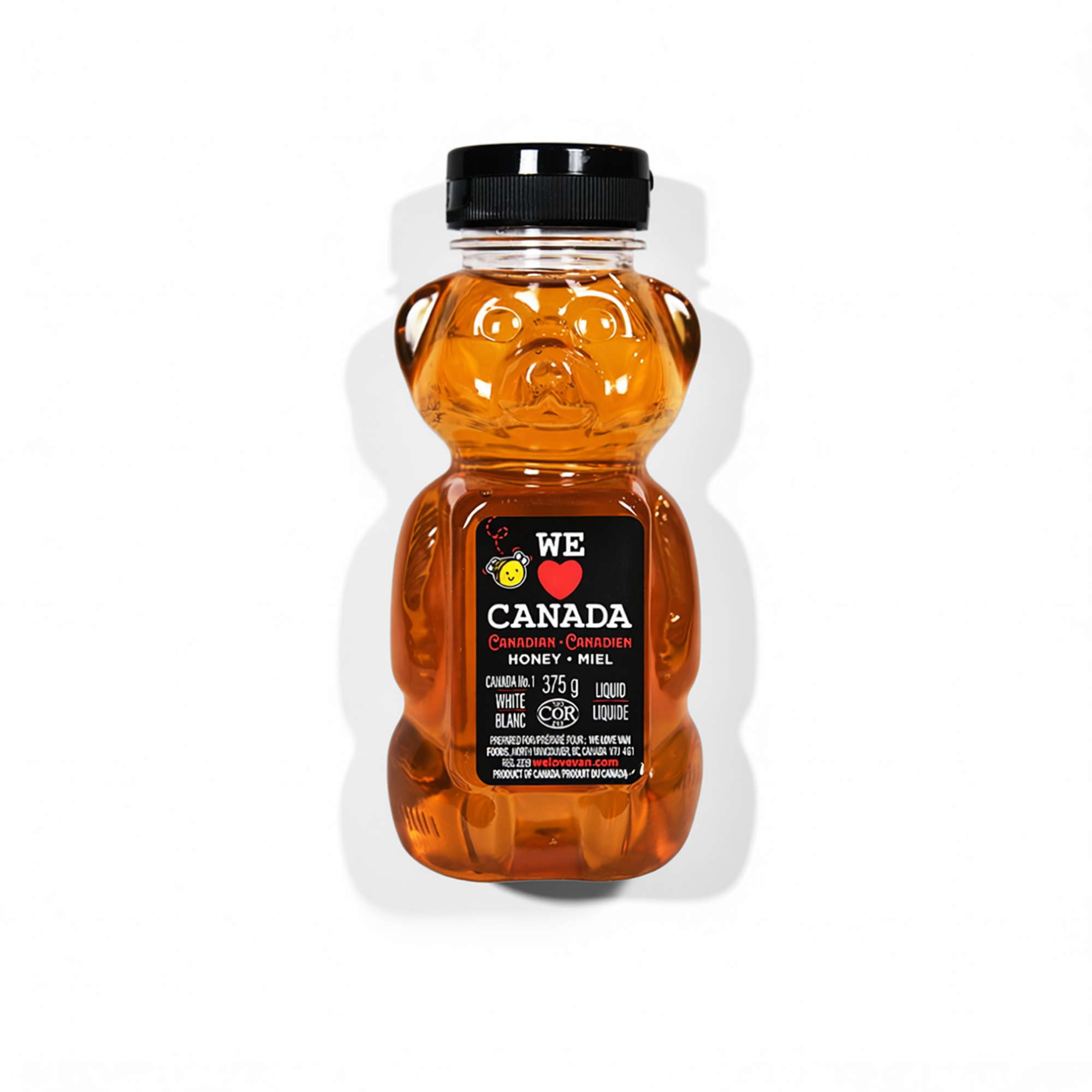 A bear-shaped bottle of Canadian honey with a black lid and a black label that says 'We Love Canada' and features a heart, honeybee, and maple leaf icons.