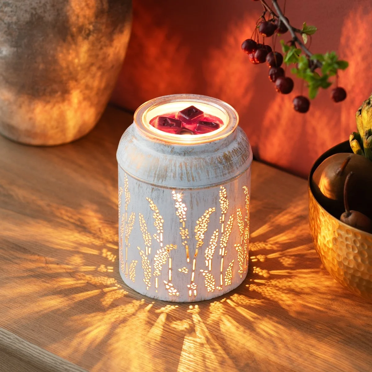 Golden Grain Scentsy Warmer glowing with warm light through metal design in a dark room